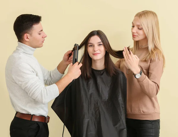 在彩色背景下与客户合作的年轻理发师 — 图库照片