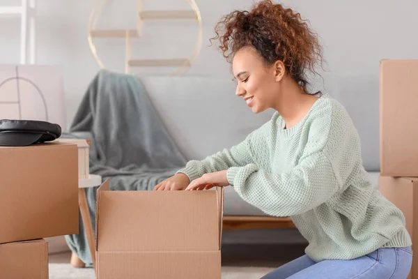 Young woman unpacking moving boxes in her new home