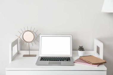 Beyaz duvarın yanında dizüstü bilgisayarı olan şık bir iş yeri.