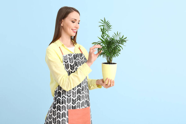 Portrait of female florist with plant on color background