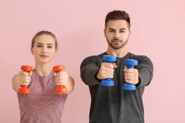 Renkli arka planda dambılları olan sportif genç çift eğitimi.