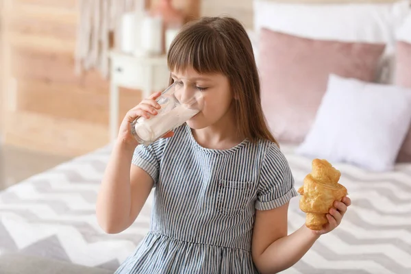 女の子飲むミルクとともにクロワッサンでベッドルーム — ストック写真