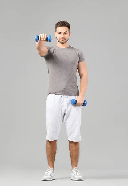 Joven Deportivo Entrenando Con Pesas Sobre Fondo Gris — Foto de Stock