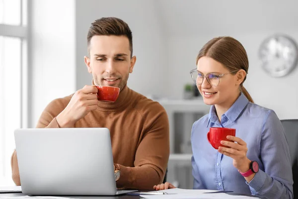 Young colleagues drinking coffee while working in office