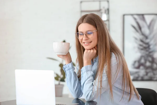 カフェでノートパソコンで仕事をしながらコーヒーを飲む若い女性 — ストック写真