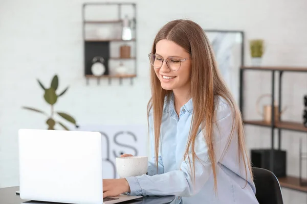 カフェでノートパソコンで仕事をしながらコーヒーを飲む若い女性 — ストック写真