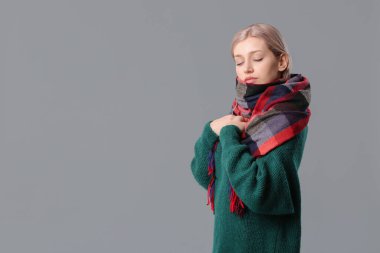 Gri arka planda şık bir eşarbı olan güzel bir genç kadın.