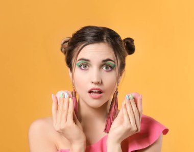 Güzel manikürlü ve renkli badem kurabiyeli genç bir kadın.