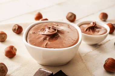 Lezzetli çikolata ezmeli kase ve masada fındık.