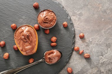 Lezzetli çikolata ezmeli kaseler ve arka planda fındıklar.