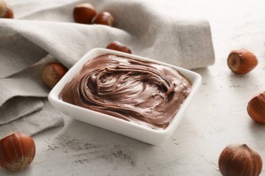 Tatlı çikolata ezmeli kase ve arka planda fındık.