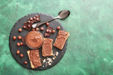 Renkli arkaplanda taze ekmek ve çikolata ezmeli levha.