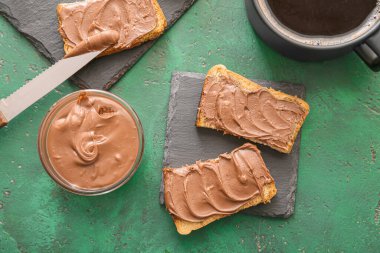 Çikolata ezmeli taze ekmek ve arka planda bir fincan kahve.