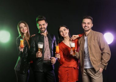 Karanlık arka planda alkollü içkileri olan mutlu gençler.