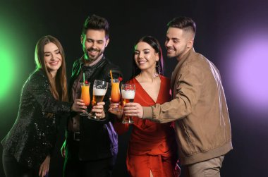 Karanlık arka planda alkollü içkileri olan mutlu gençler.
