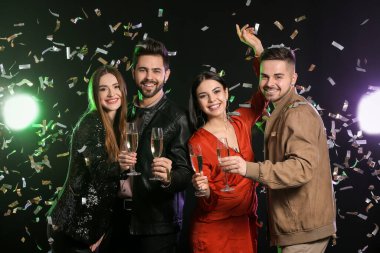 Karanlık arka planda şampanya kadehleri olan mutlu insanlar.