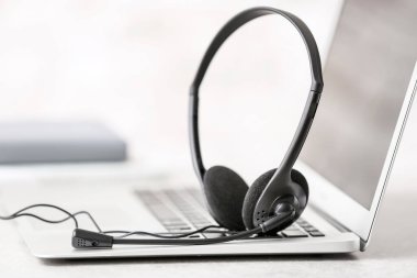 Kulaklık ve dizüstü bilgisayar, ofisteki teknik destek ajanının masasında.