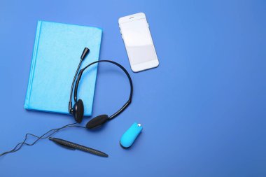 Renkli arka planda kulaklık ve cep telefonu olan defter