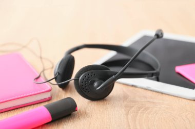 Ofisteki teknik destek ajanının masasında kulaklık, tablet bilgisayar ve defter var.