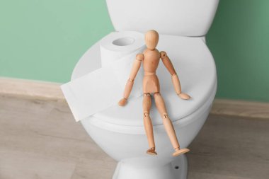 Tuvalet kağıdı ve ahşap insan figürü tuvalette.
