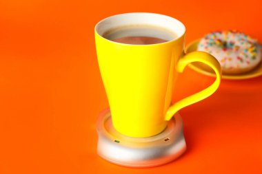 Arka planda ısıtıcısı olan bir fincan kahve.