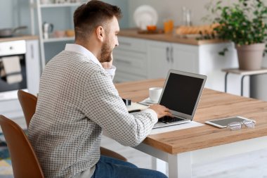 Bilgisayarlı genç adam evde çalışıyor.