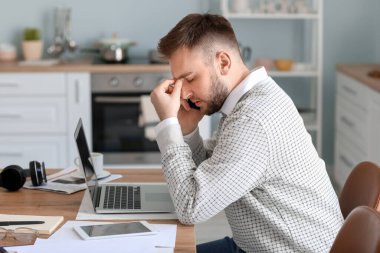 Evde çalışan yorgun genç adam.