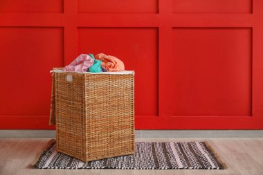 Çamaşır sepetinin yanında renkli duvar var.