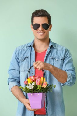Renkli arka planda çiçek demeti olan yakışıklı bir adam.