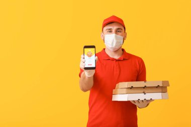 Tıbbi maskeli ve cep telefonlu gıda dağıtım şirketinin erkek kuryesi.