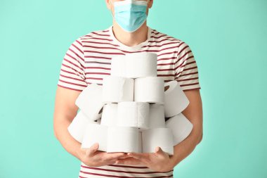 Koruyucu maskeli ve arka planında tuvalet kağıdı olan bir adam. Koronavirüs salgını kavramı