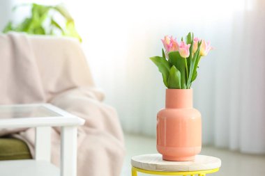 Oturma odasının içinde lale çiçekleri olan şık bir vazo.