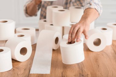 Evde tuvalet kağıdı yığını olan olgun bir adam. Koronavirüs salgını kavramı