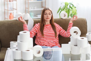 Evde bir yığın tuvalet kağıdıyla meditasyon yapan bir kadın. Koronavirüs salgını kavramı