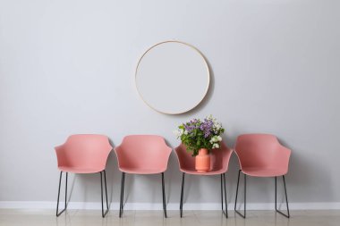 Gri duvarın yanında güzel leylak çiçekli şık koltuklar.