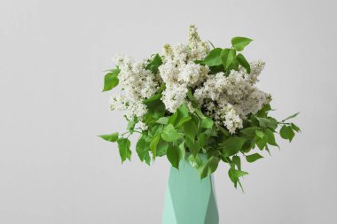 Gri arkaplanda güzel leylak çiçekleri olan vazo