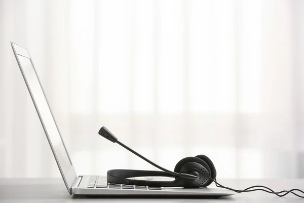 Headset and laptop on table of technical support agent in office