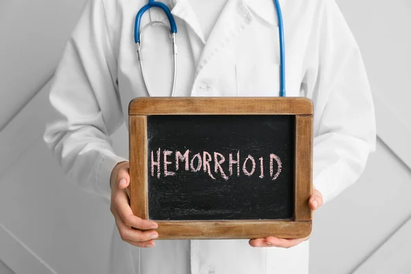 Doctor Holding Chalkboard Text Hemorrhoid Light Background — Stock Photo, Image