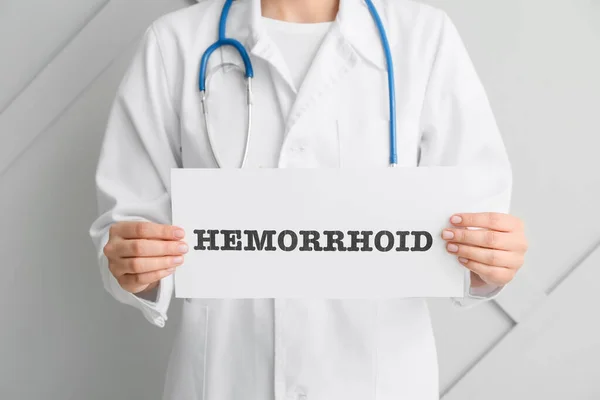 Doctor Holding Paper Word Hemorrhoid Light Background — Stock Photo, Image