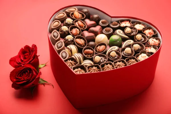 Herzförmige Schachtel Mit Schokoladenbonbons Und Blumen Auf Farbigem Hintergrund — Stockfoto