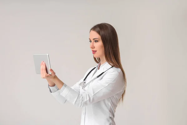 拥有灰色背景平板电脑的年轻女医生 — 图库照片