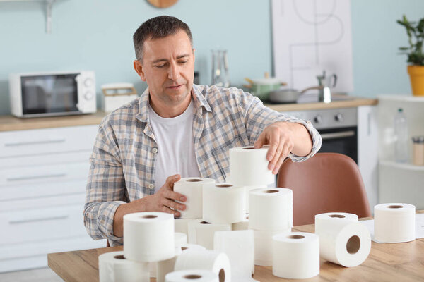 Mature man with heap of toilet paper at home. Concept of coronavirus epidemic