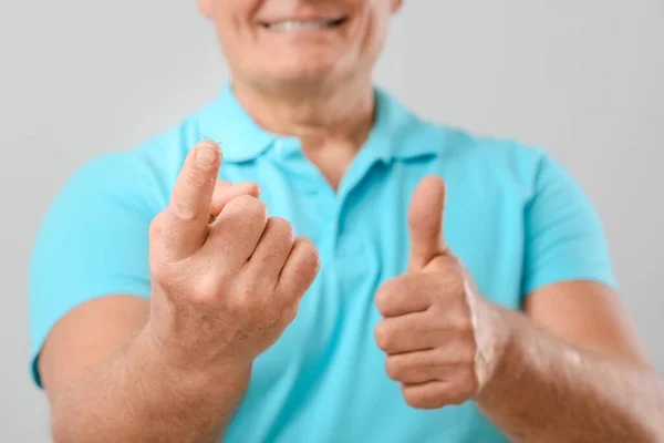 Volwassen Man Met Contactlens Met Duim Omhoog Tegen Lichte Achtergrond — Stockfoto