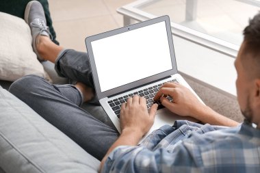 Evde dizüstü bilgisayarı olan yakışıklı adam.