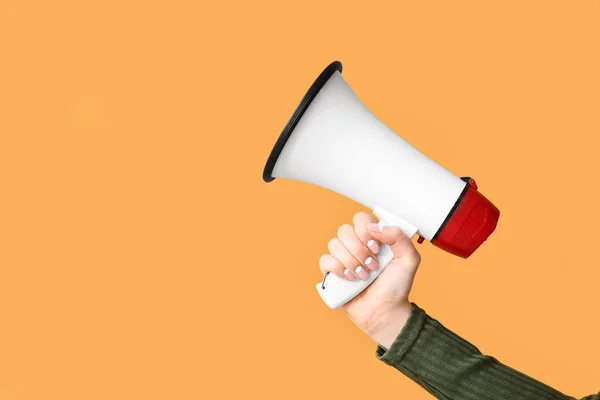 Female hand with megaphone on color background