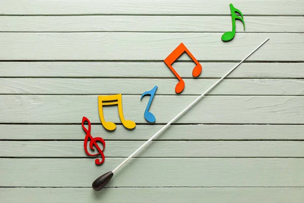 Note symbols and conductor\'s stick on wooden background