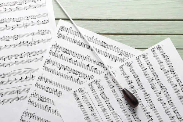 Note sheets and conductor\'s stick on wooden background