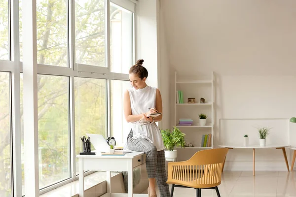 Evde çalışan dizüstü bilgisayarı olan genç bir kadın.