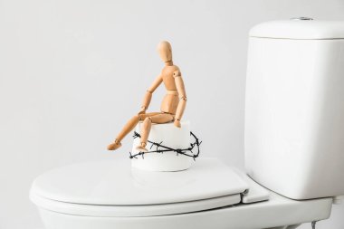 Tuvalet kağıdı rulo, dikenli tel ve arka planda tahta insan figürü. Hemoroit konsepti