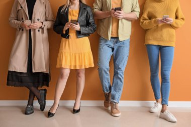 Renk duvarının yanında cep telefonu olan insanlar